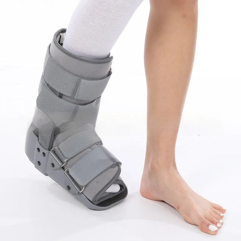 Grey achilles tendon rehabilitation boot with adjustable straps and a rigid plastic shell on a rubber sole.