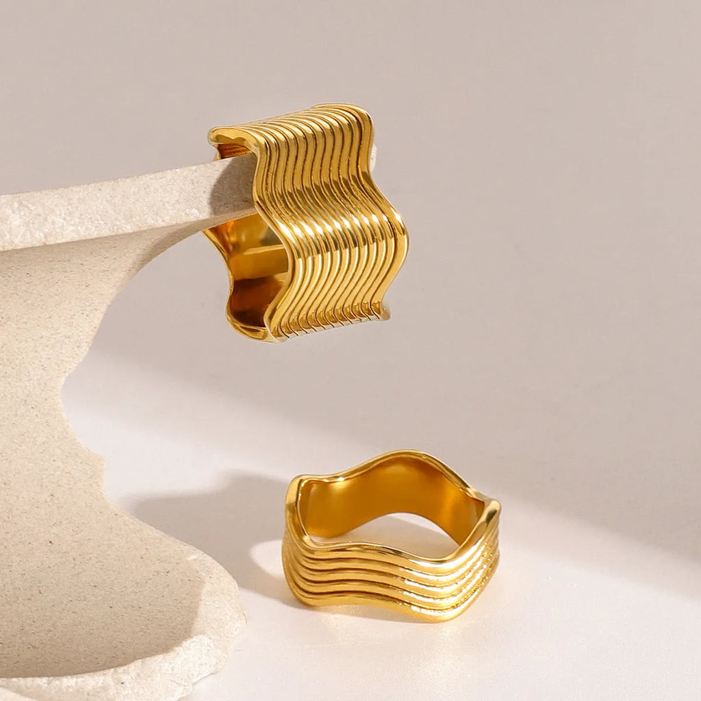 Stainless steel wide band ring with an embossed geometric wave pattern, shown in an electroplated colour.