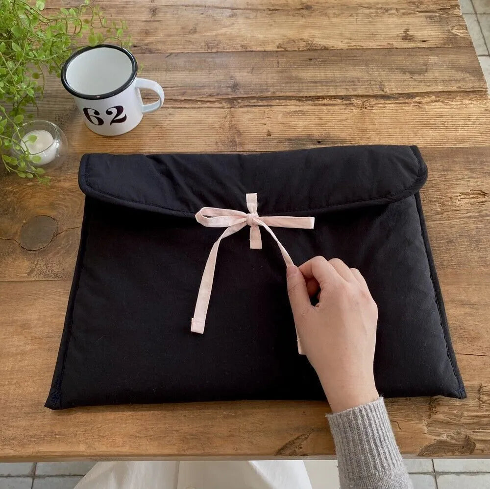 Women's black and white quilted laptop bag with bow detail and striped pattern