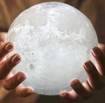 3D printed white moon lamp on wooden stand showing detailed lunar surface texture.