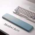 Square black silica gel mouse pad with raised keyboard support area and integrated wrist rest on a wooden desk.