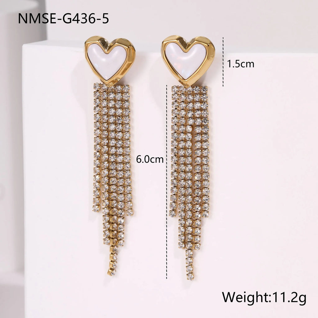 Close-up of a women's stainless steel earring with a heart shape and a dangling geometric tassel featuring diamond and star details.