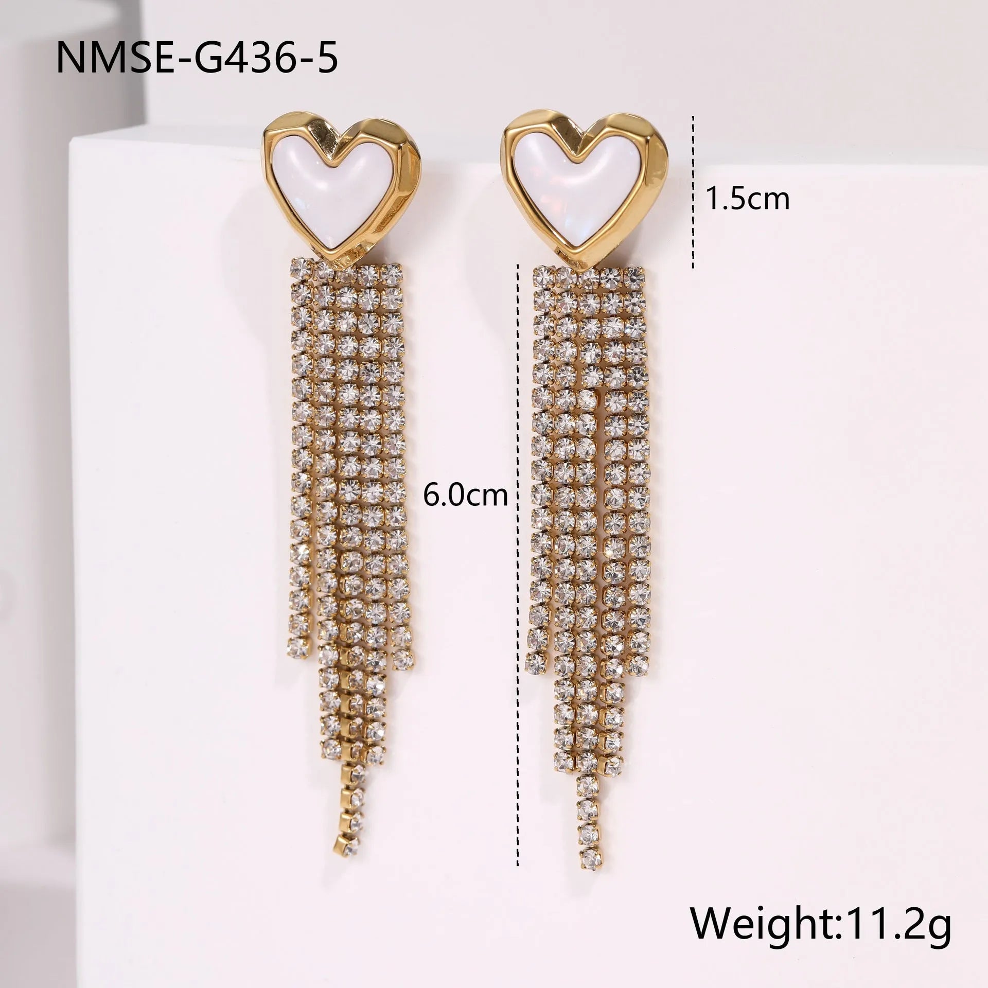 Close-up of a women's stainless steel earring with a heart shape and a dangling geometric tassel featuring diamond and star details.