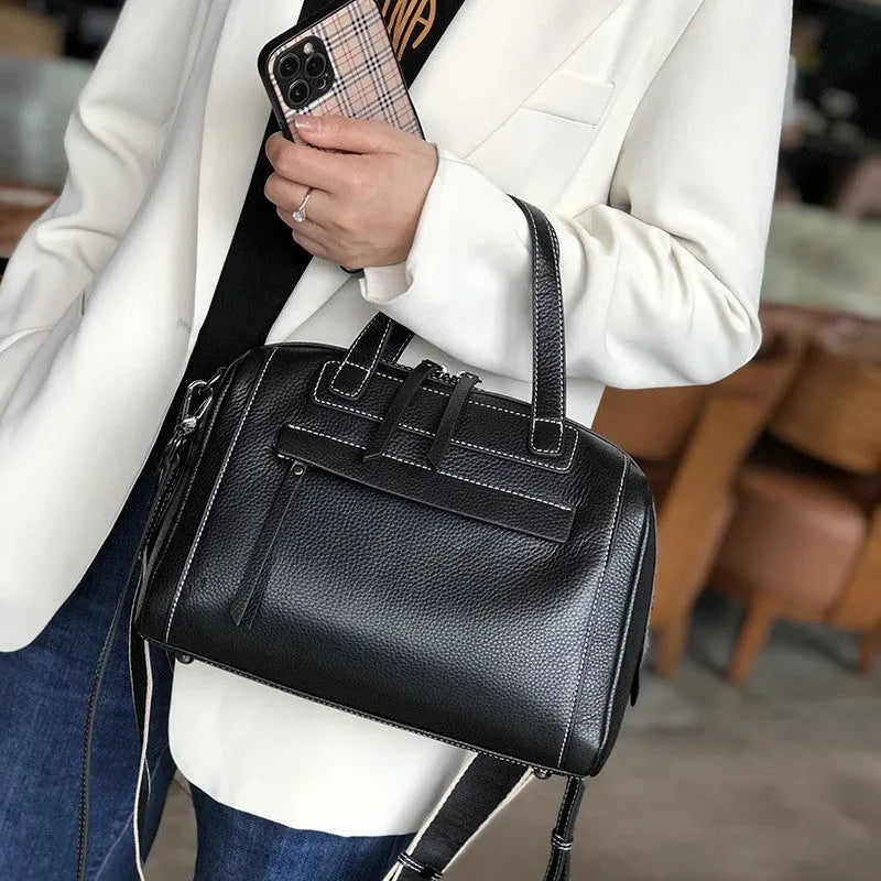 Soft black cowhide leather messenger bag with lychee pattern, showing internal phone and camera pockets.