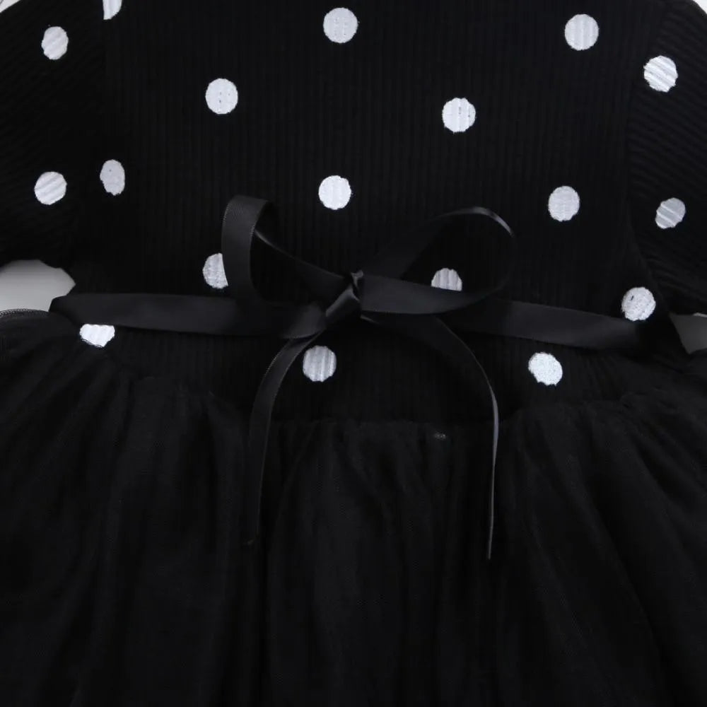 Baby girl wearing a long sleeve black tutu lace dress for a first birthday or christening event.