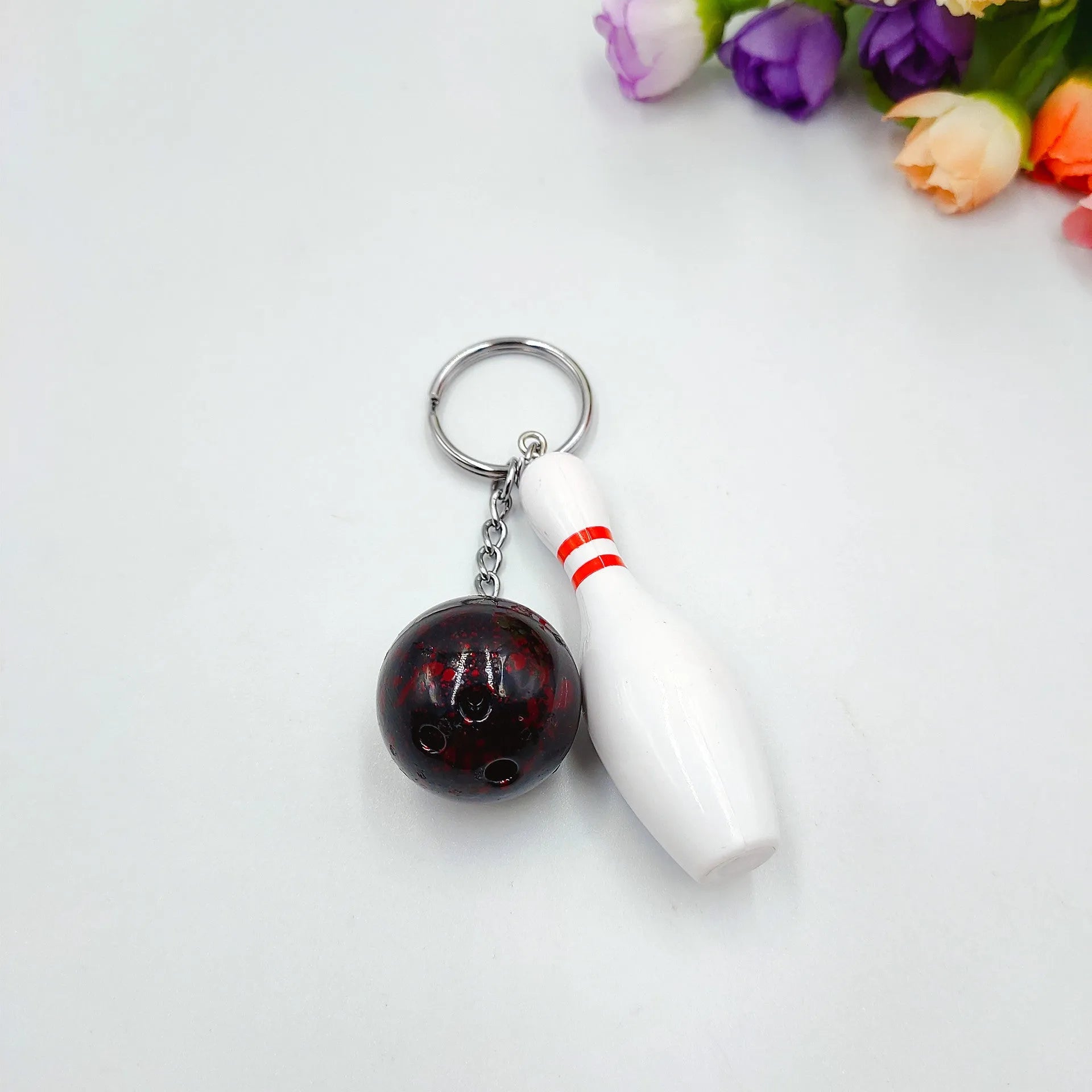 Mini bowling ball keychain pendant in PVC metal showing four colour options: dark red, blue, purple, green