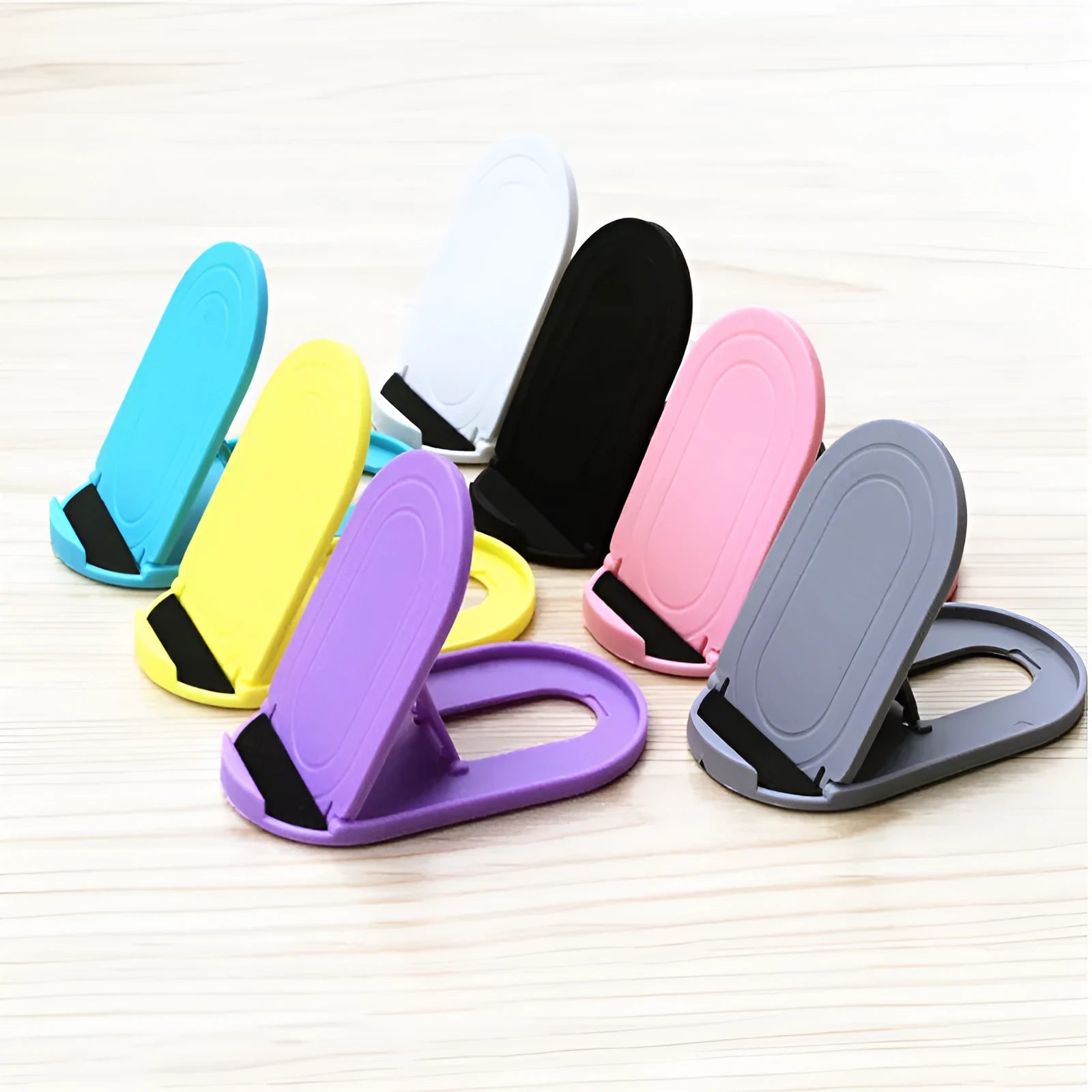 Plastic adjustable bracket mobile phone stand in six colour choices on a desk.