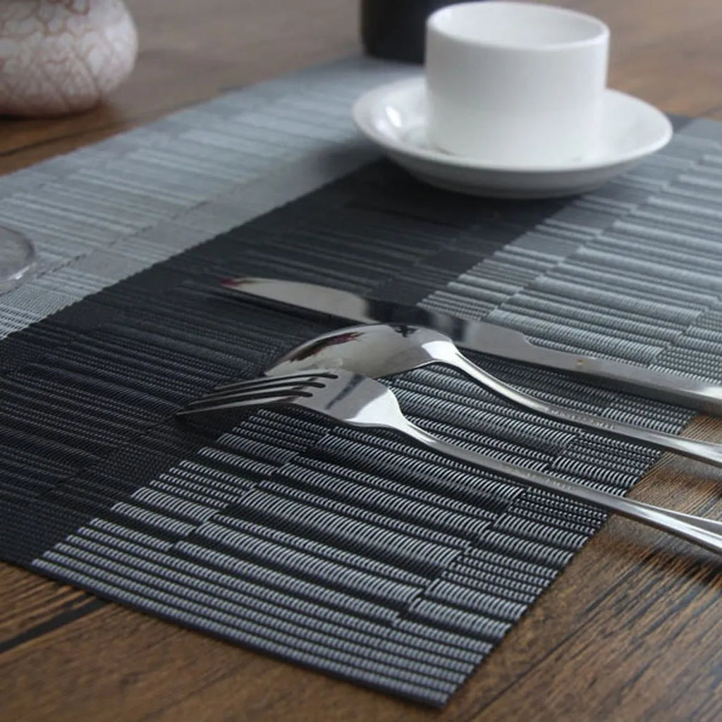 Modern non-slip PVC dish mat with gradient bamboo pattern in black, placed on a wooden dining table.