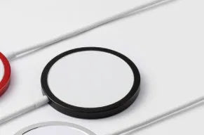Silver metal Magsafe magnetic wireless charger for Apple iPhone on a desk.