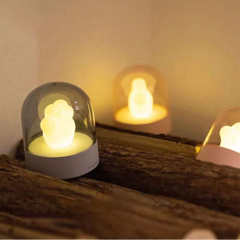 Grey cat paw shaped USB rechargeable night light with music box on a desk.