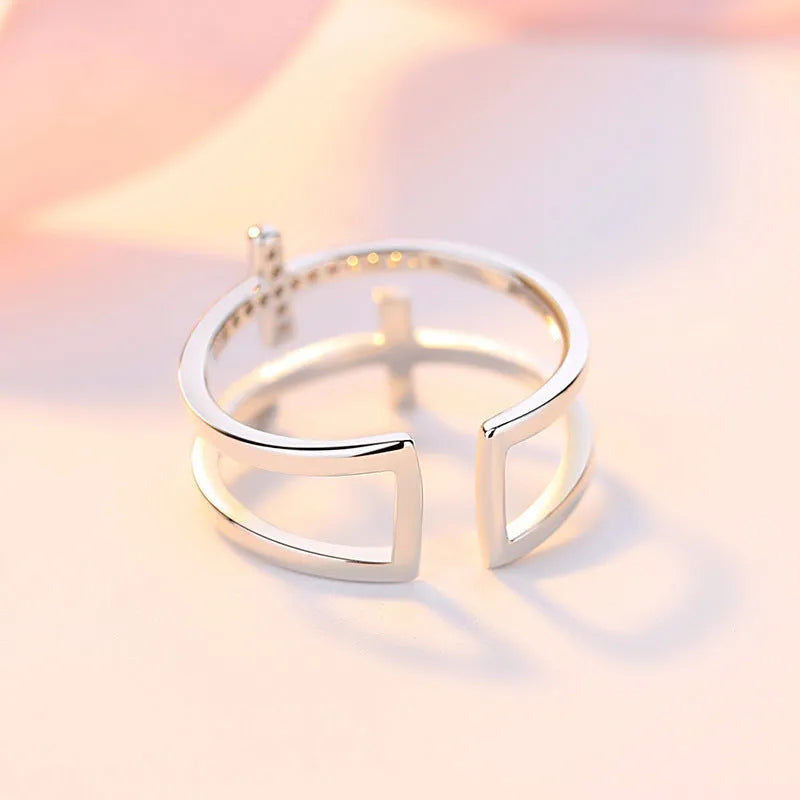 Adjustable open copper ring with geometric double cross design and inlaid zircon stones in gold colour finish.