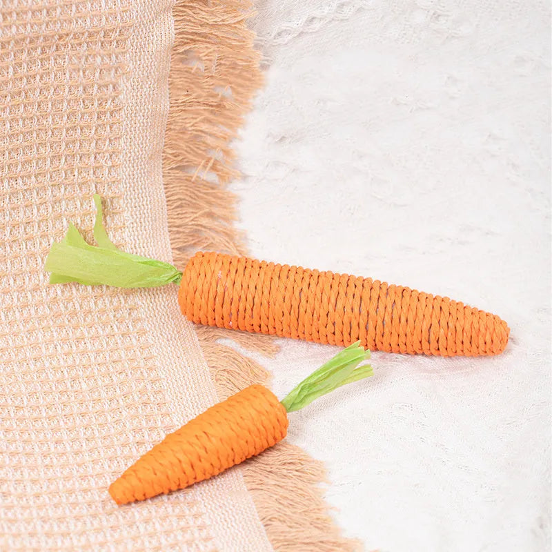 Assortment of colourful interactive cat toys including plastic carrots, ringing stones, fabric sticks, paper toys, and chewing sticks.