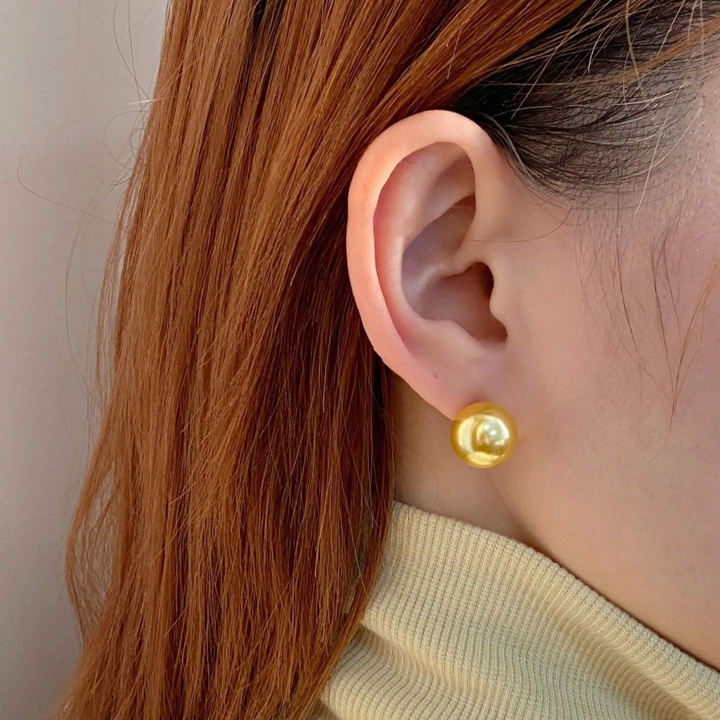 A pair of large pearl stud earrings with a geometric silver setting on a white background.