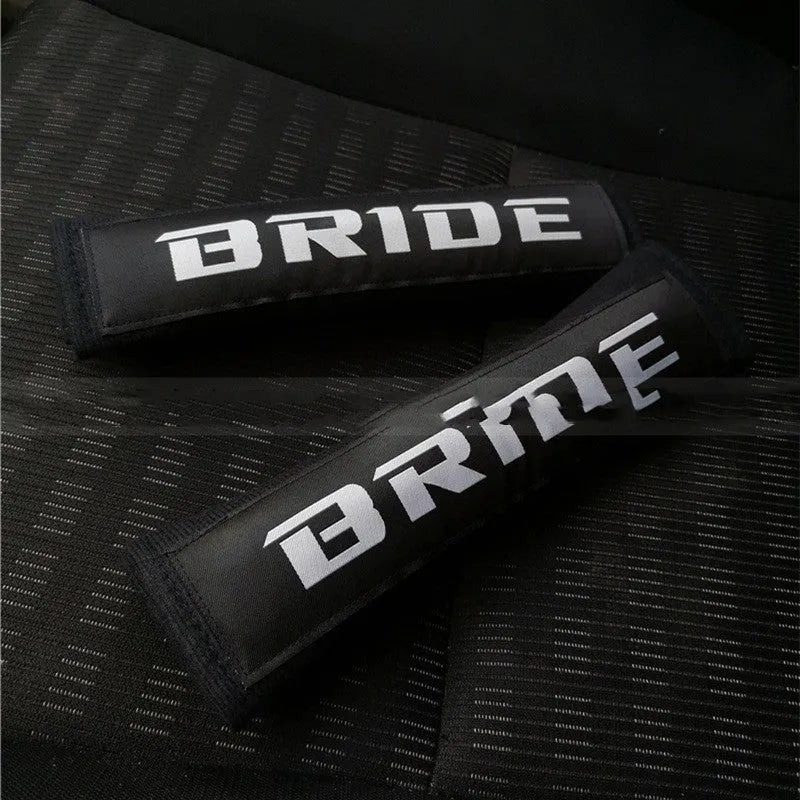Pair of black car seatbelt shoulder pads showing embroidery detail and thickness