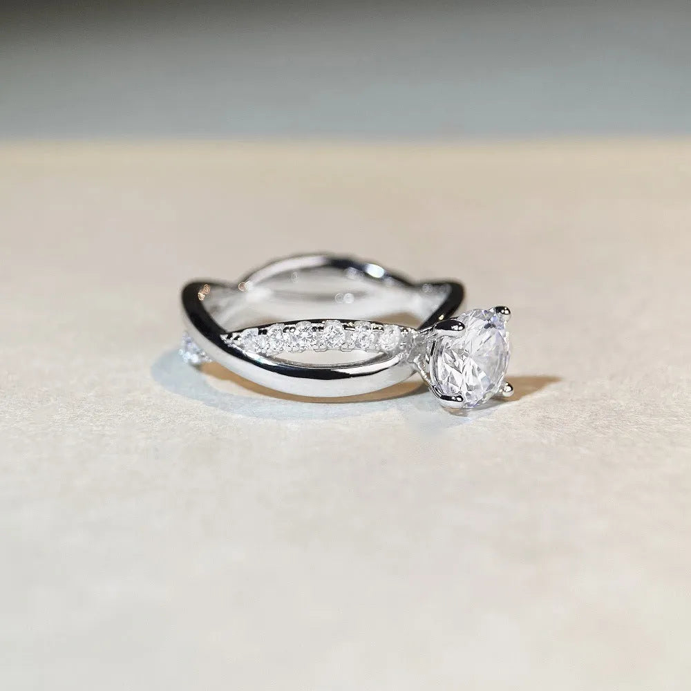 Silver ring with a 1 karat moissanite stone in a four-claw setting and a geometric twisted arm band.