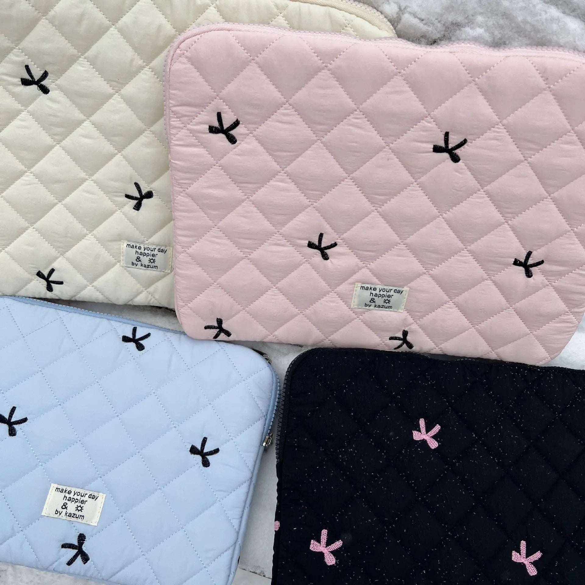 White nylon laptop bag with embroidered rhombus pattern and fabric bow, shown alongside black, light blue, and light pink colour options.