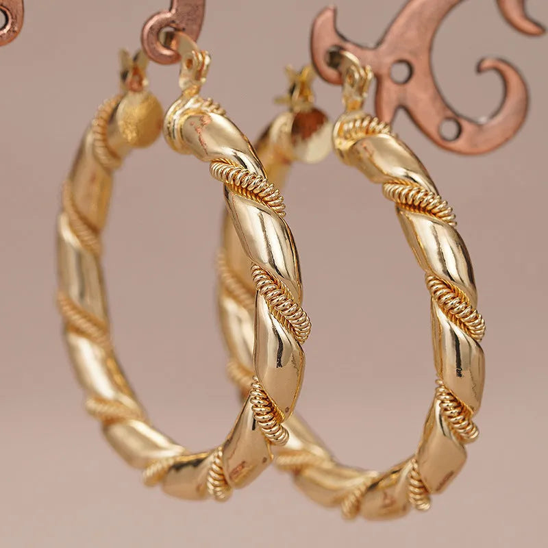 Pair of golden geometric copper earrings with ring and line design details.