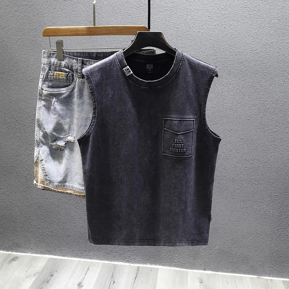 A man's solid black loose-fit cotton sleeveless T-shirt with a straight hem, laid flat.