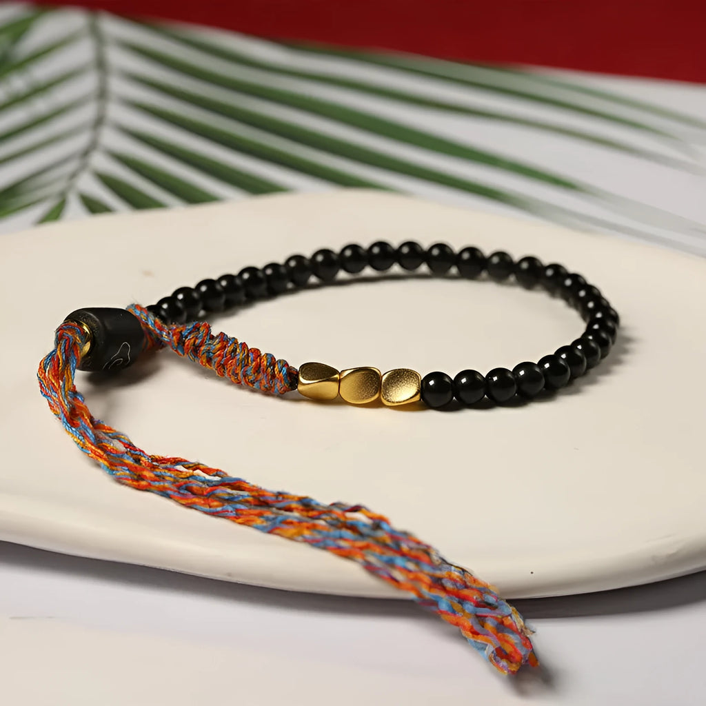 Hand-woven obsidian carrying strap bracelet showing textured weave and 4mm width