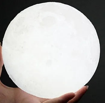 3D printed white moon lamp on wooden stand showing detailed lunar surface texture.