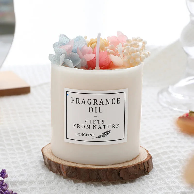 Decorative scented candle with dried flowers inside, shown with wooden chip base and gift box packaging.