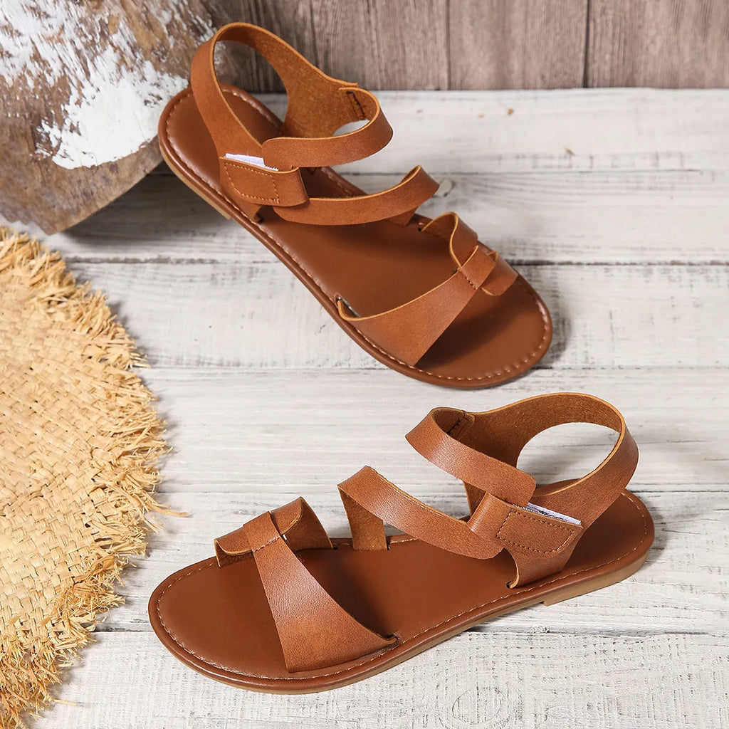 Women's brown flat sandals with Velcro fastening and rubber sole on a white background.
