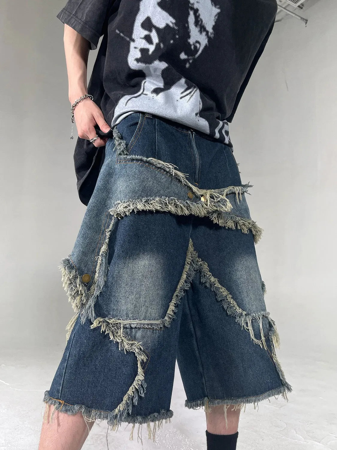 Blue denim shorts with frayed hems and star patches in loose fit American retro style