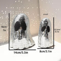 Silver glass Halloween ghost ornament with mosaic inlaid surface on a desktop.
