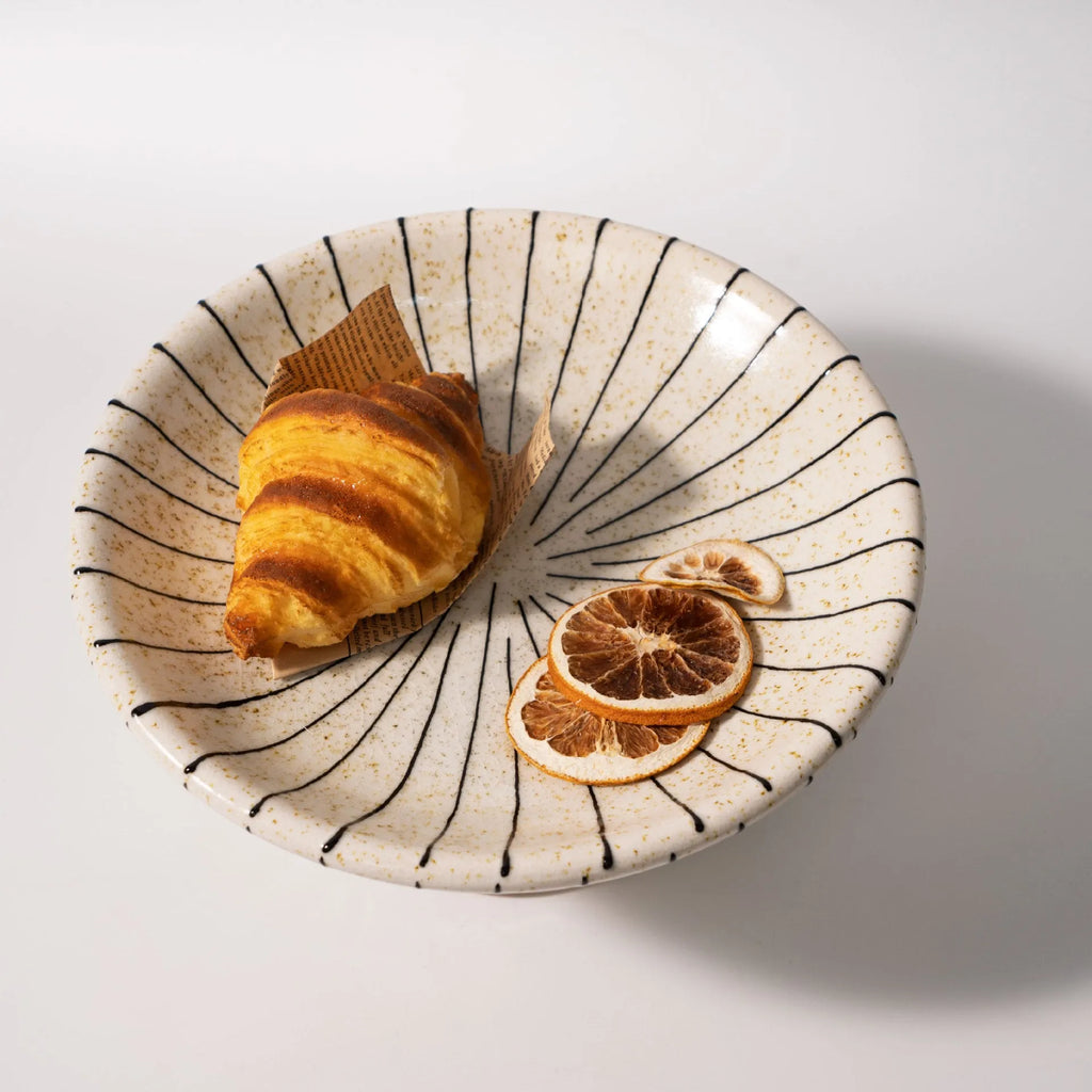 Black and white striped plastic resin fruit plate on a wooden surface.
