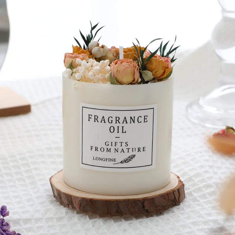Decorative scented candle with dried flowers inside, shown with wooden chip base and gift box packaging.