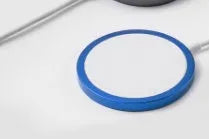 Silver metal Magsafe magnetic wireless charger for Apple iPhone on a desk.