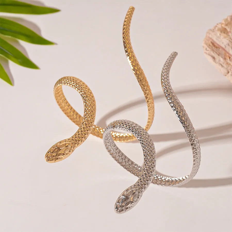 Gold tone snake-inspired bracelet and ring set with exaggerated twisted winding design on white background