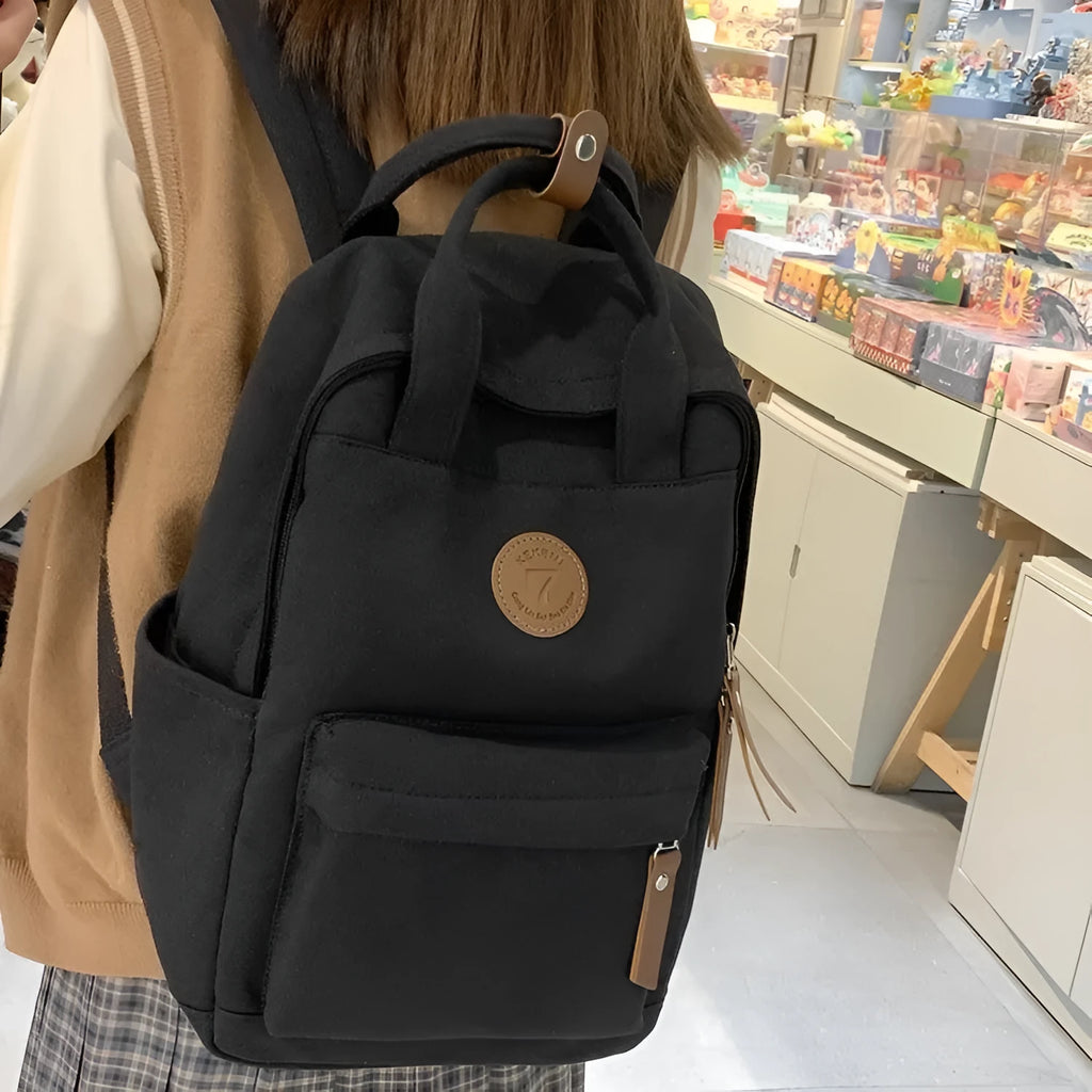 Black Oxford cloth backpack with curved shoulder straps on solid background
