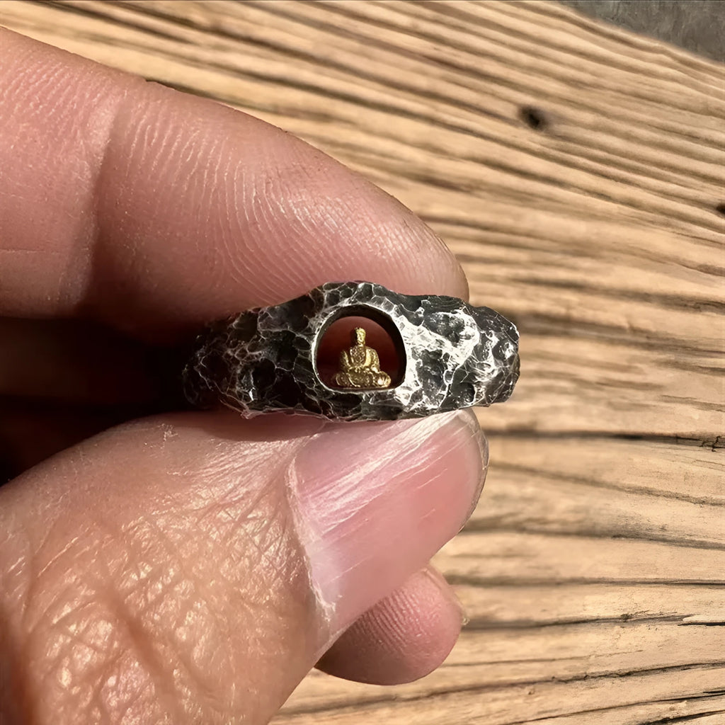 Close-up of a hand-forged copper Grotto Buddha ring with a rough rock texture on a size 8 finger.