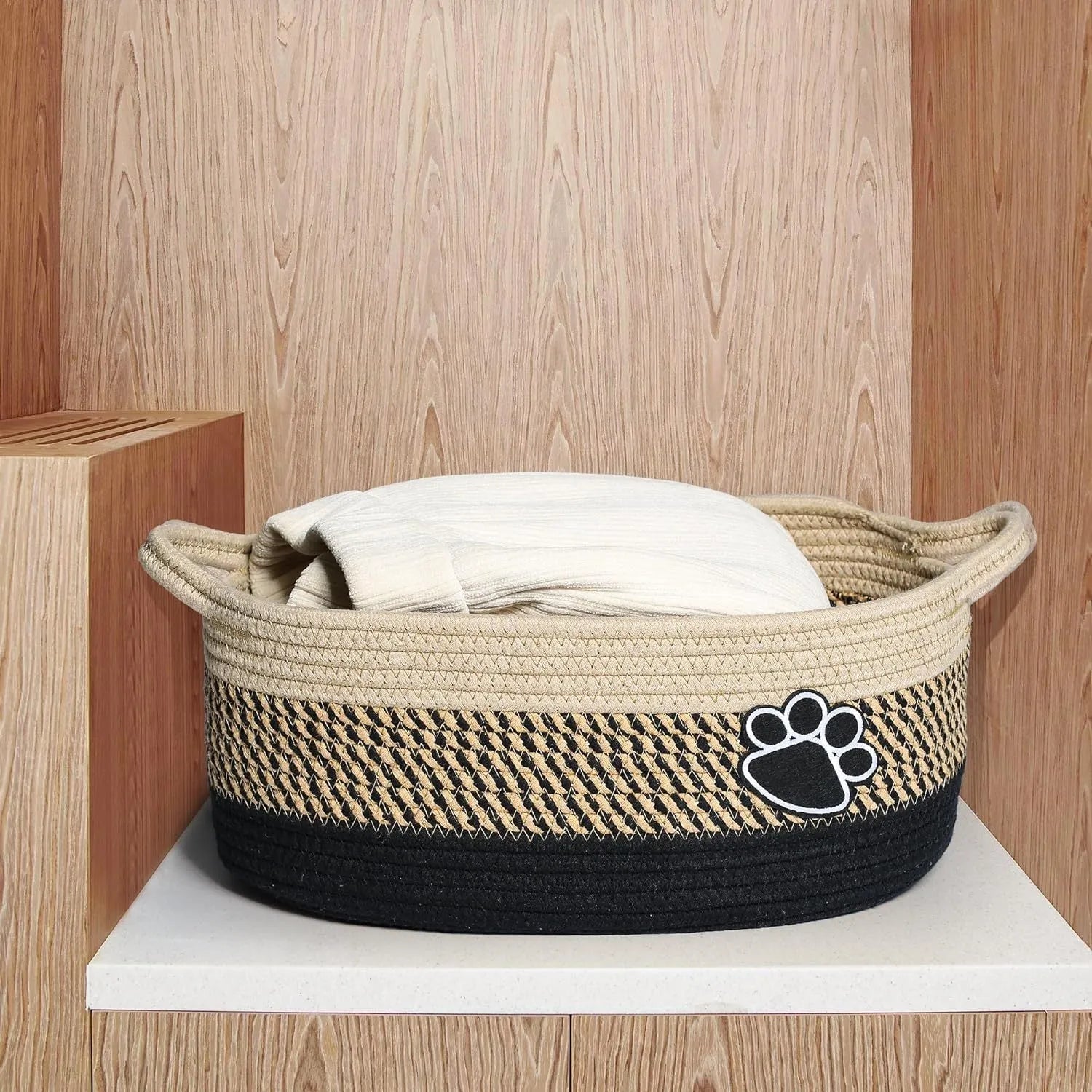 Light beige handmade cotton rope storage basket with handle on a wooden surface.