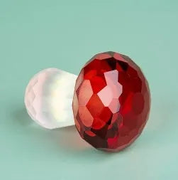 Colourful geometric crystal mushroom decoration in transparent, green, red, or yellow on a white background.
