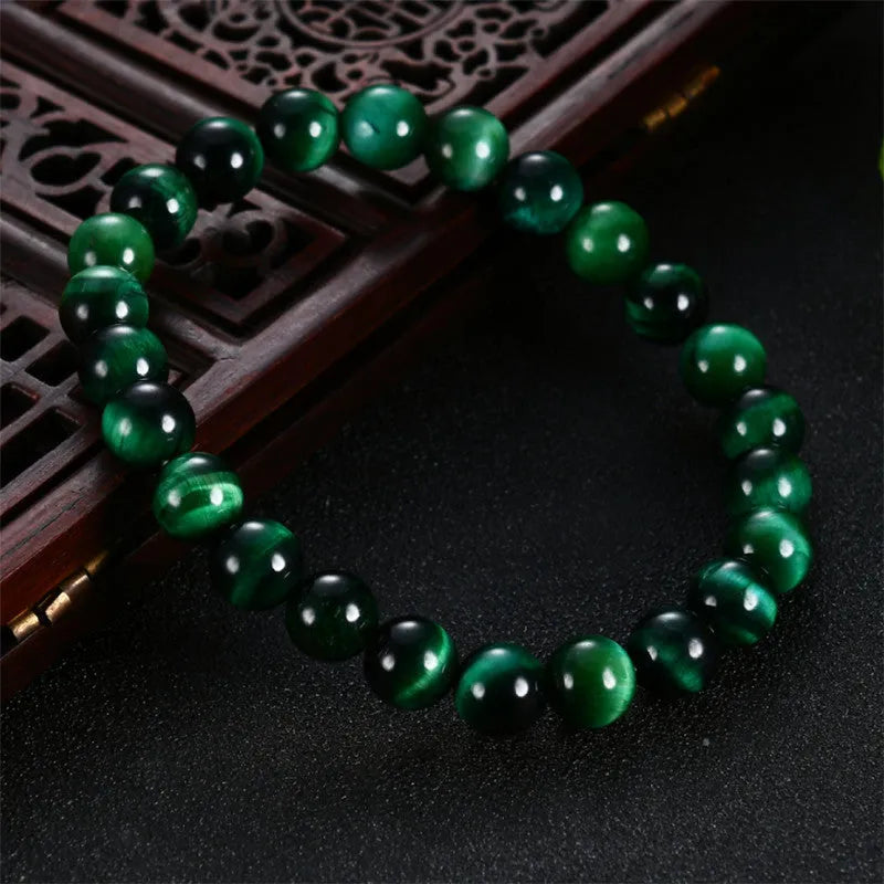 Green Tiger Eye stone geometric bead bracelet on wrist, showing polished surface and banding.