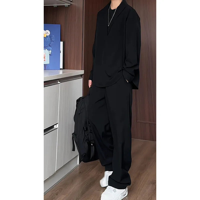 Man wearing a black slim fit long sleeve polo shirt and matching trousers from a casual two-piece set.