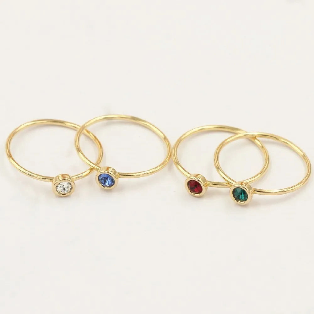 Women's 14K gilded copper knuckle ring with zircon accents in green, shown on a model's finger.
