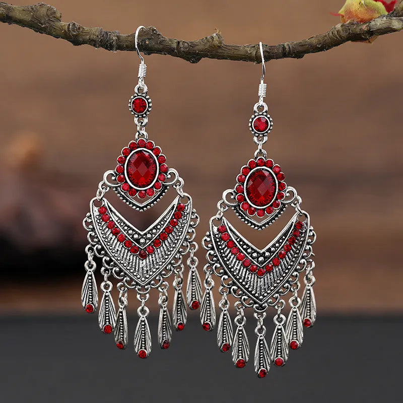 Long purple fringe drop earrings with retro crystal design on a white background.