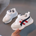 Children's white sneakers with Velcro fastening and rubber sole shown from side view