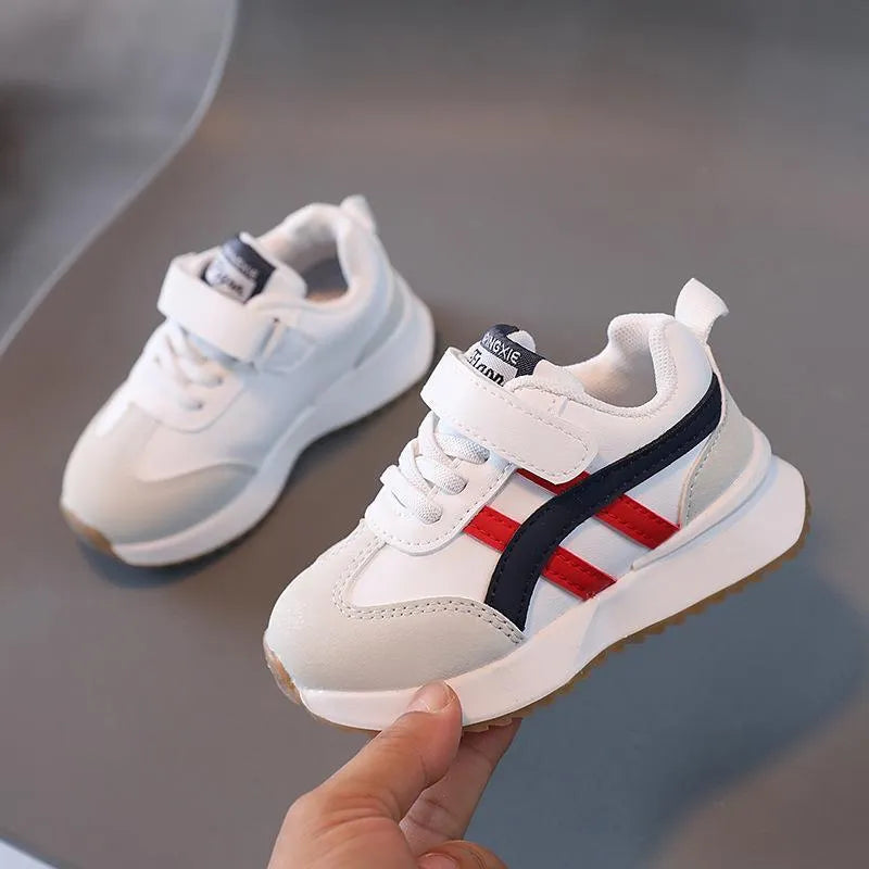 Children's white sneakers with Velcro fastening and rubber sole shown from side view