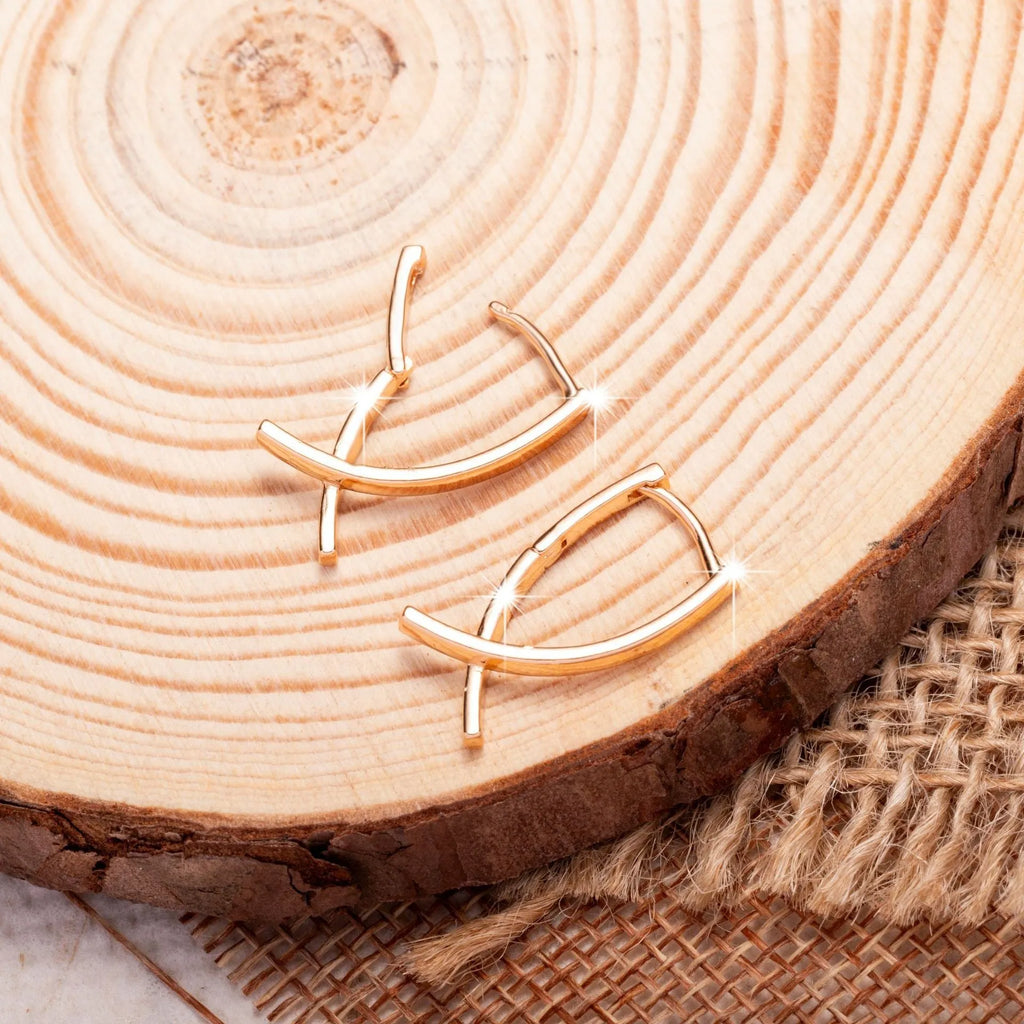 A pair of rose gold-coloured copper earrings in a detailed cross shape.