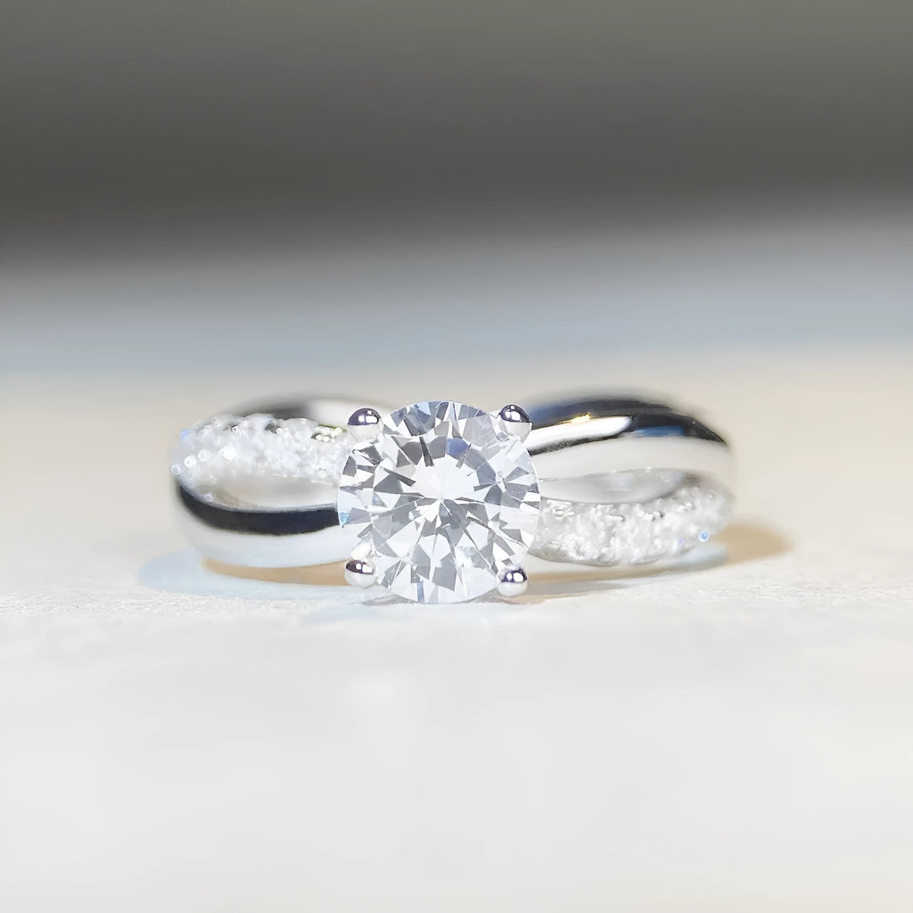 Silver ring with a 1 karat moissanite stone in a four-claw setting and a geometric twisted arm band.