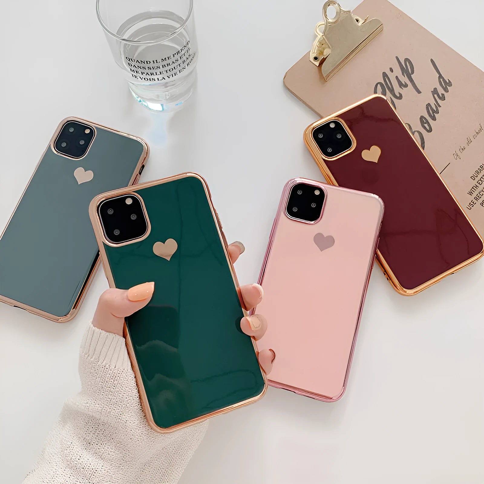 Solid colour TPU back cover case for iPhone on a table, shown in blue, claret, pink, and green.