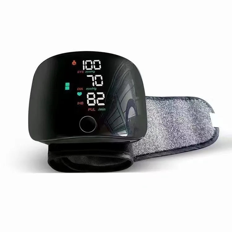 Black wrist blood pressure monitor with USB charging port and digital display.