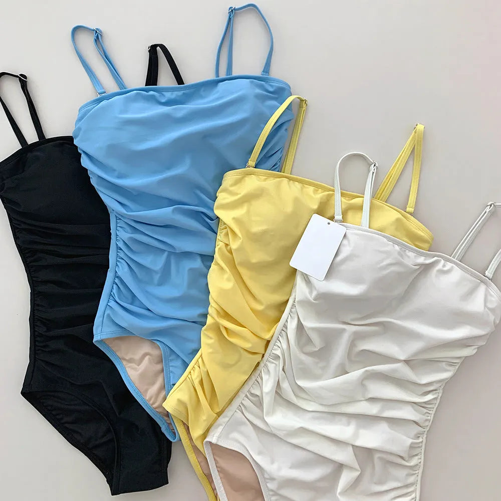 Blue sling style one-piece swimsuit with belly pleating on a mannequin.