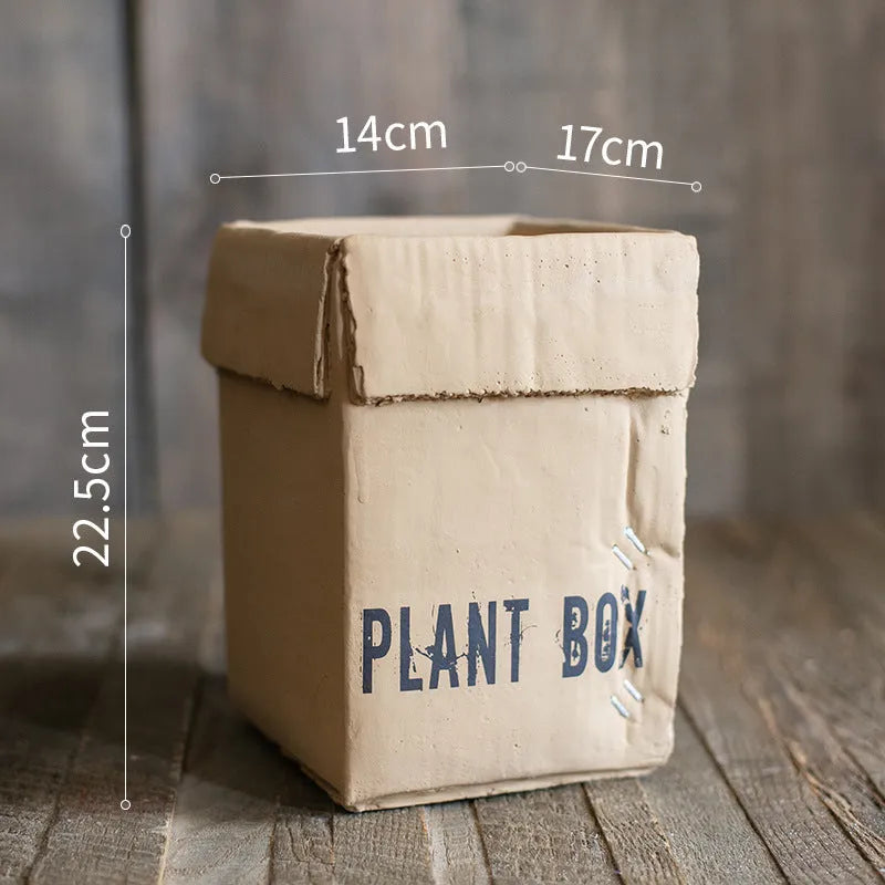 Cement flowerpot with brown paper box texture and bottom drainage holes on a floor.