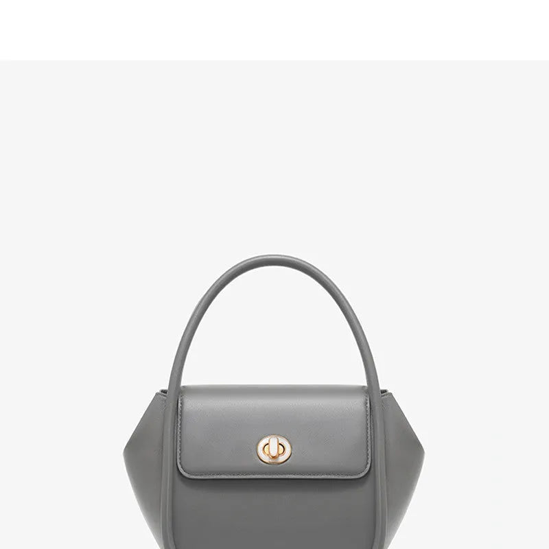 Brown leather wing-shaped tote bag with a buckle detail and latch closure, shown with a single cross-body strap.