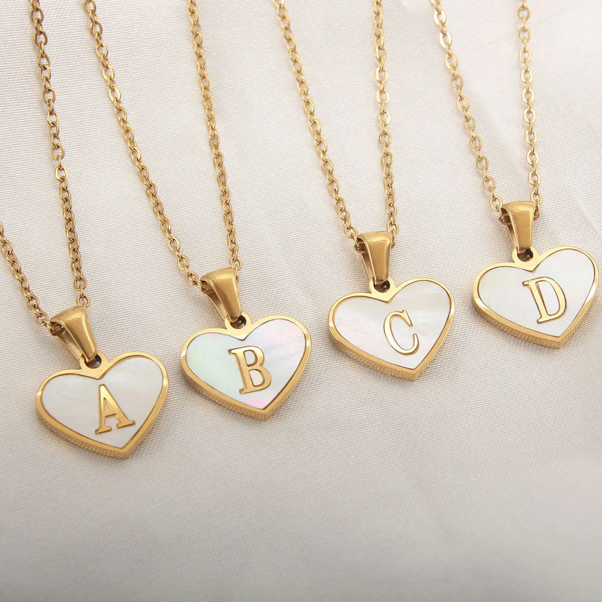 Gold-plated heart necklace with white shell pendant showing initial engraving on stainless steel chain